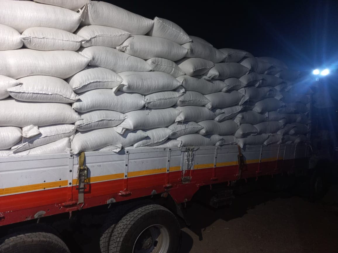 Bagged grain stacked high on a departing truck at night